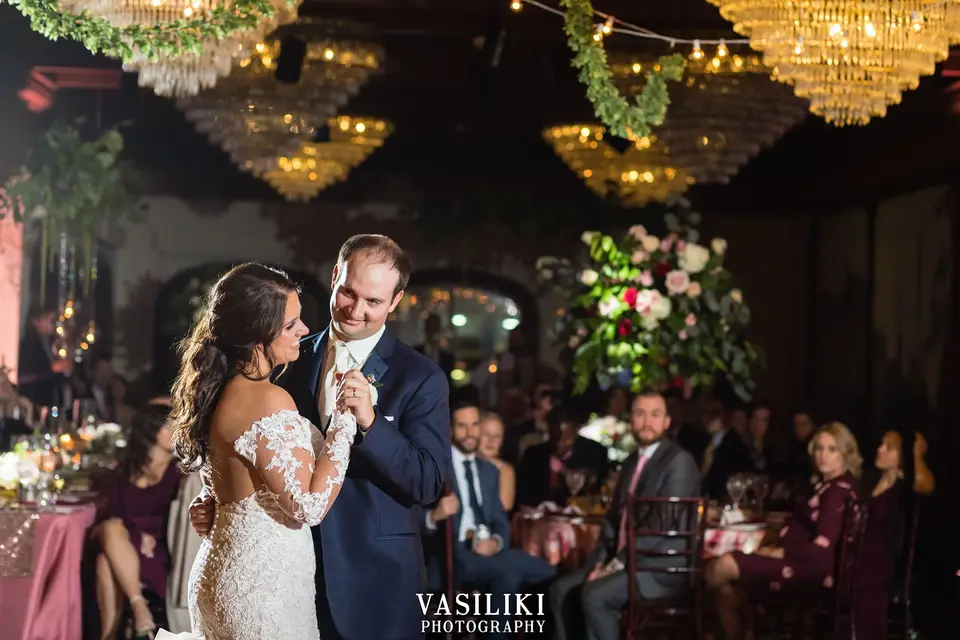 Becky and Matt sharing a first dance in a chandelier-lit ballroom while seated guests watch