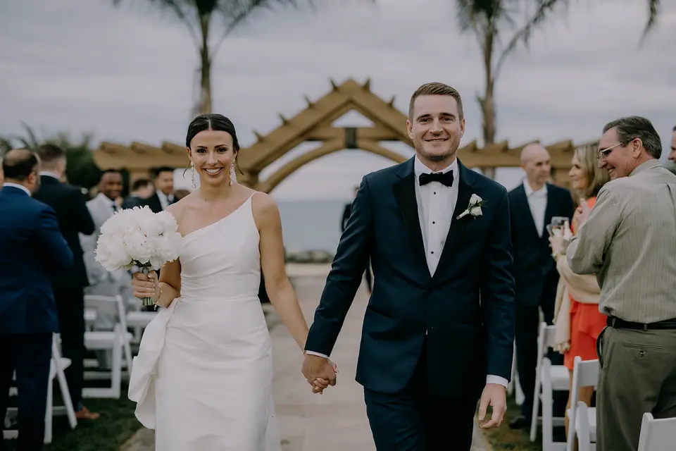 Bride and groom holding hands and smiling as they walk down the aisle after their Herrington on the Bay ceremony
