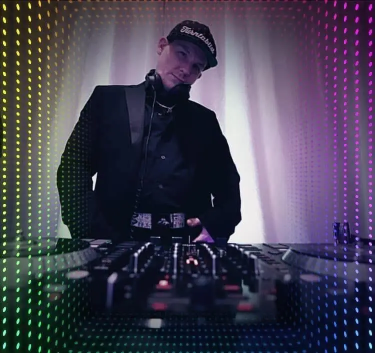 DJ in a black jacket and cap with headphones behind a DJ controller, framed by colorful dotted lights